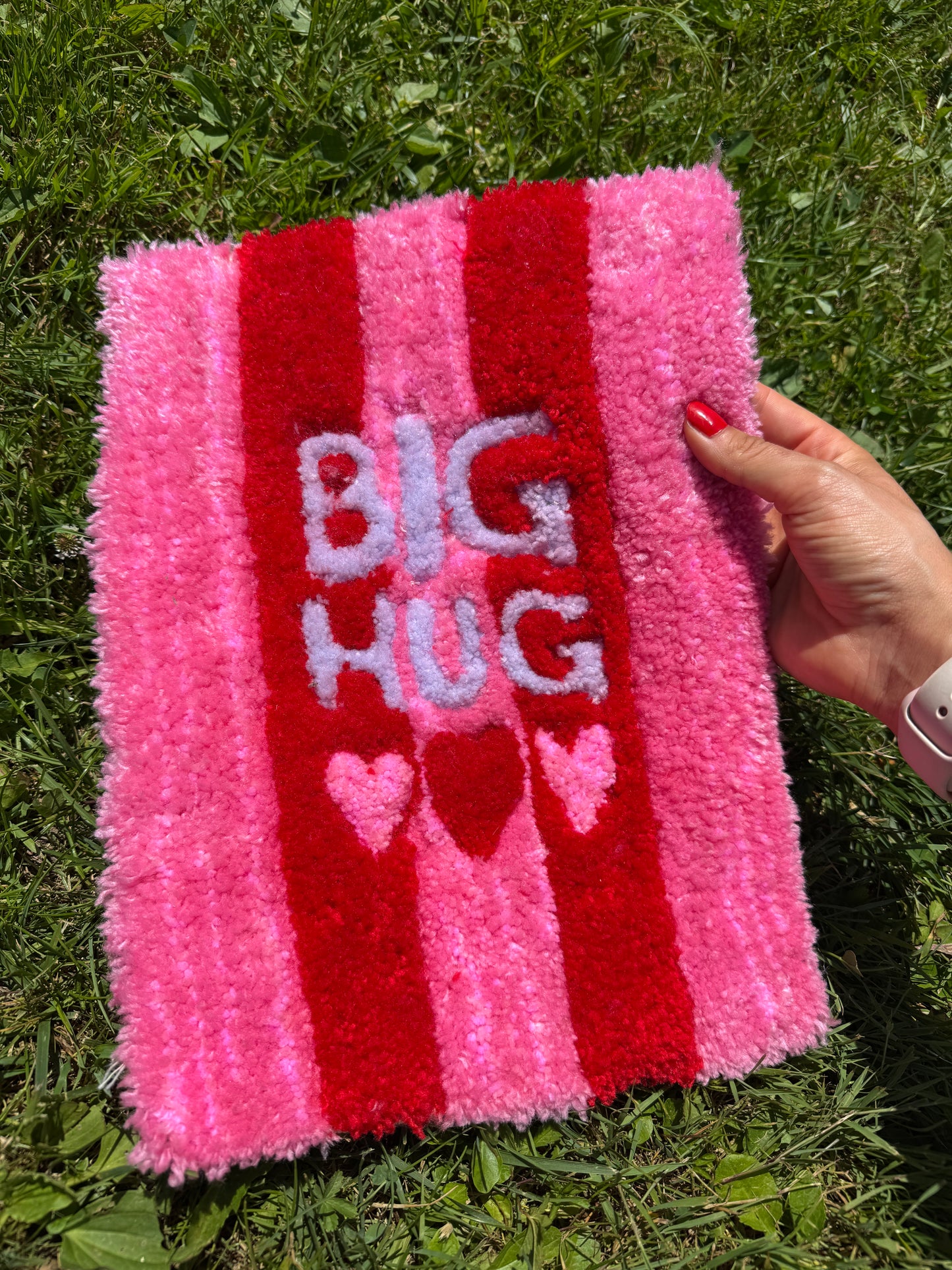 Tapis tufté à la main Aurea Big Hug, rectangulaire, avec larges rayures roses et rouges, texte Big Hug et trois cœurs, design simple et chaleureux pour intérieur